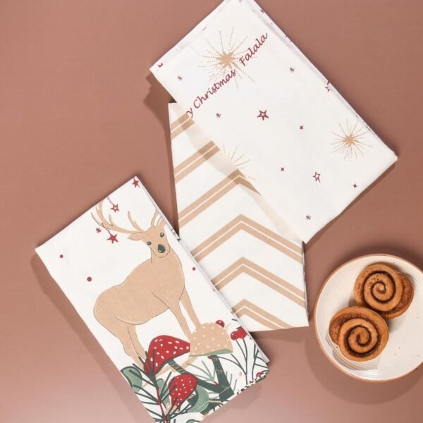 45x70 cm cotton tea towel with reindeer print folded beside holiday decor (2) 45x70 cm cotton tea towel with reindeer print folded beside holiday decor