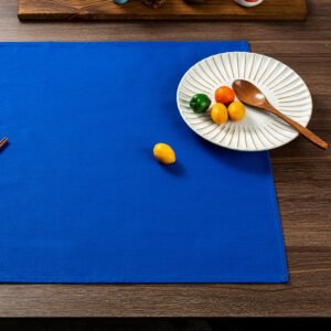 Blue solid cotton napkin folded neatly beside tableware
