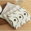 White cotton napkin with subtle printed border and embroidered hotel logo